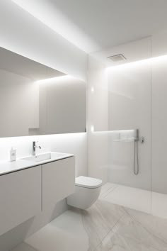 a bathroom with a toilet, sink and shower stall in it's white color scheme