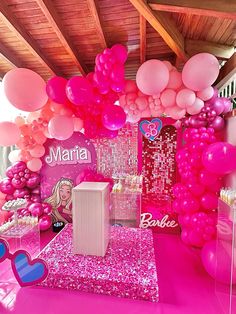 pink and white balloons are hanging from the ceiling in front of a barbie themed birthday party