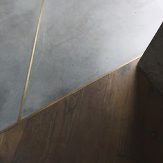 the corner of a room with a wooden floor and gray walls, has gold trim on it