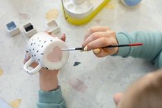 a person holding a cup with a paintbrush in their hand and painting the inside