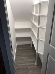 an empty room with white shelves and wood flooring