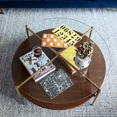 a coffee table with books, magazines and a cactus sitting on it in front of a blue couch