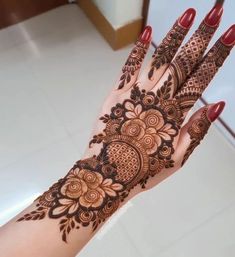 a woman's hand with henna tattoos on it, showing the intricate design