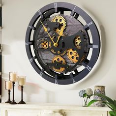 a clock that is on the wall in front of a fireplace with candles around it