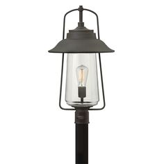 an outdoor post light with a clear glass shade on the top and black metal frame