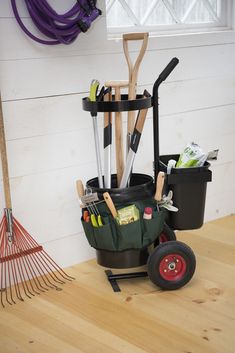 there are many different tools in the storage bins on this table and behind it is a garden tool rack