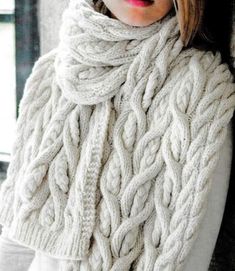 a woman wearing a white sweater and scarf with a knitted cable around her neck