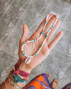 a woman's hand with beads and bracelets on it