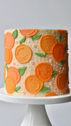 a white cake with oranges and green leaves on it