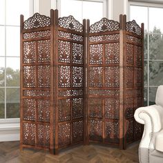 the room divider is made out of wood and has intricate carvings on each side