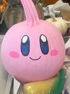 a pink pumpkin with blue eyes sitting on top of plastic wrap