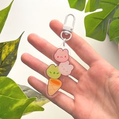 a hand holding a keychain with an animal and ice cream charm on it