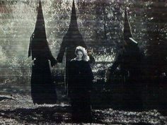 two women dressed in black are walking through the woods