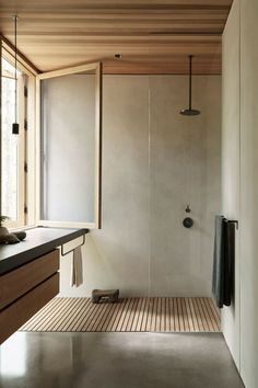 a bathroom with a wooden floor and white walls, along with an open shower stall