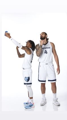 two basketball players standing next to each other with their arms in the air and one holding a bottle