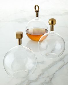 two clear glass vases sitting on top of a white marble counter next to a bottle filled with liquid