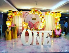 the one sign is surrounded by balloons and flowers in front of a backdrop with butterflies