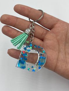 a hand holding a glass keychain with blue and green stars on the bottom