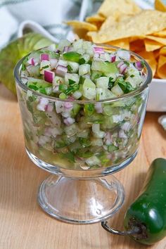 a glass bowl filled with cucumber and onion salad next to tortilla chips