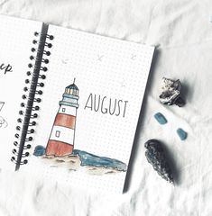 a spiral notebook with an image of a lighthouse on it and the words august written in cursive writing