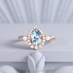 a blue and white diamond ring on top of a white surface with pearls around it