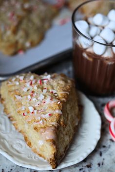 a slice of cake sitting on top of a white plate next to a cup of hot chocolate