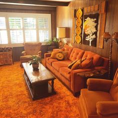 a living room filled with orange furniture and lots of pillows on the couches in front of large windows