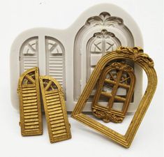 three pieces of gold and white are shown in front of an arch with shutters