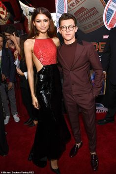 two people standing next to each other on a red carpet