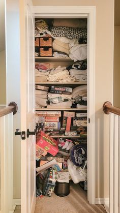 an open closet with clothes and other items on the shelves in front of it's door