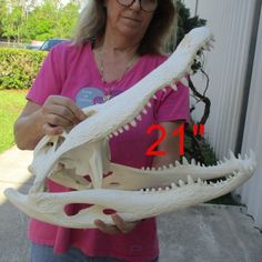 a woman holding a fake alligator's head in front of a house with the number 21 on it