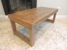 a wooden coffee table sitting in front of a fire place with a fireplace behind it