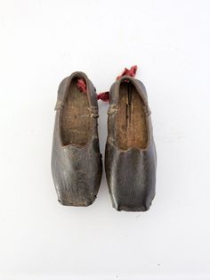 From our Heritage Collection This is a pair of antique hand cobbled leather shoes. The little shoes feature wood soles engraved 1884 on the left foot. Aged, black leather shapes the feet. A red ribbon accents the back of the right shoe. CONDITION In good condition with wear consistent with age and use. MEASUREMENTS Length: 6.5 inch .. 16.5 cm Width: 2.5 inch ... 6.4 cm Height: 2.25 inch... 5.7 cm 71306 1800s Shoes, Historical Shoes, Bags Online Shopping, Antique Clothing, Buy Shoes Online, Buy Shoes, Childrens Shoes, Red Ribbon, Vintage Shoes