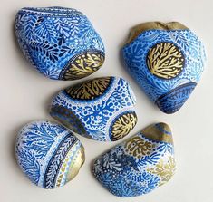 four blue and gold painted rocks sitting next to each other