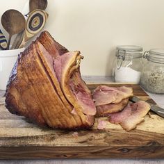 a large piece of meat sitting on top of a cutting board next to utensils