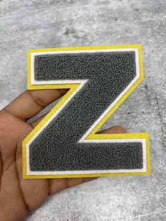 a hand holding a small patch with the letter z in it's center and yellow border