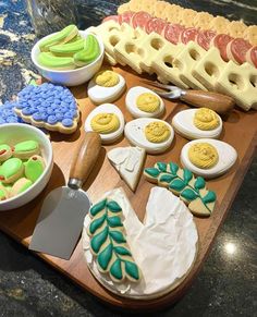 an assortment of decorated cookies and pastries on a cutting board with other food items