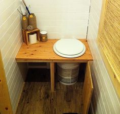 there is a toilet in the corner of this small room with wood flooring and white walls