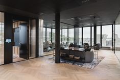 an office with large windows and wooden flooring in front of glass walls that look out onto the city