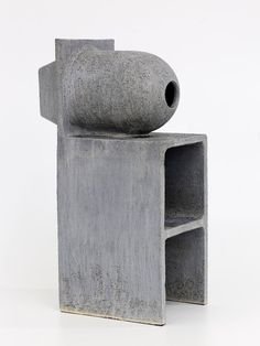 a concrete sculpture with a hole in the middle and a shelf below it on a white background