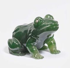 a green frog figurine sitting on the ground