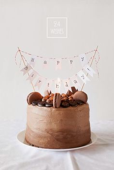 a birthday cake with chocolate frosting and nuts on top is sitting on a plate