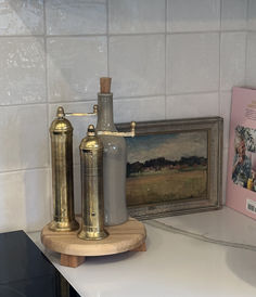 an old fashioned oil lamp sitting on top of a counter next to a framed painting