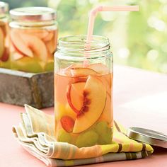 two mason jars filled with sliced peaches and apple slices on a pink table cloth