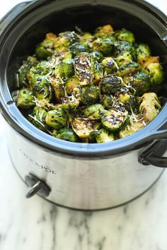 a pot filled with cooked broccoli on top of a marble counter