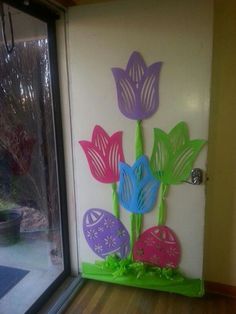 a door decorated with paper flowers and easter eggs in front of an open glass window