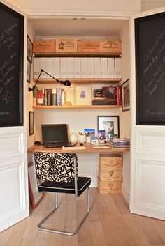 a home office with chalkboard on the wall and wooden flooring, along with a chair