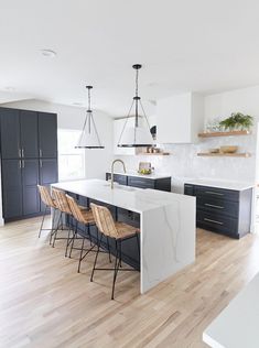 a kitchen with an island and bar stools in the center, surrounded by black cabinets