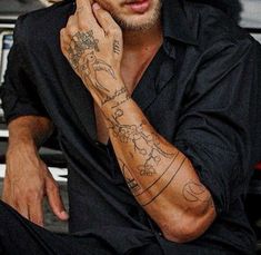 a man with tattoos on his arm sitting down