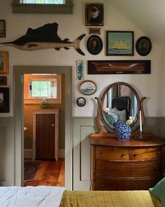 a bedroom with a dresser, mirror and pictures on the wall